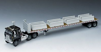 INTERNATIONAL TRANSTAR COE with WORKHORSE LOGO on a WILSON FLATBED TRAILER with Jersey Barrier Load with chains , in 1/64